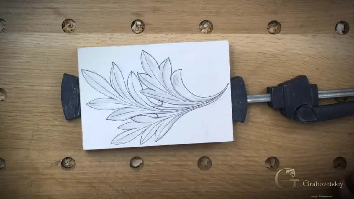 Drawing of a leaf on a white faced blank, held by two clamps