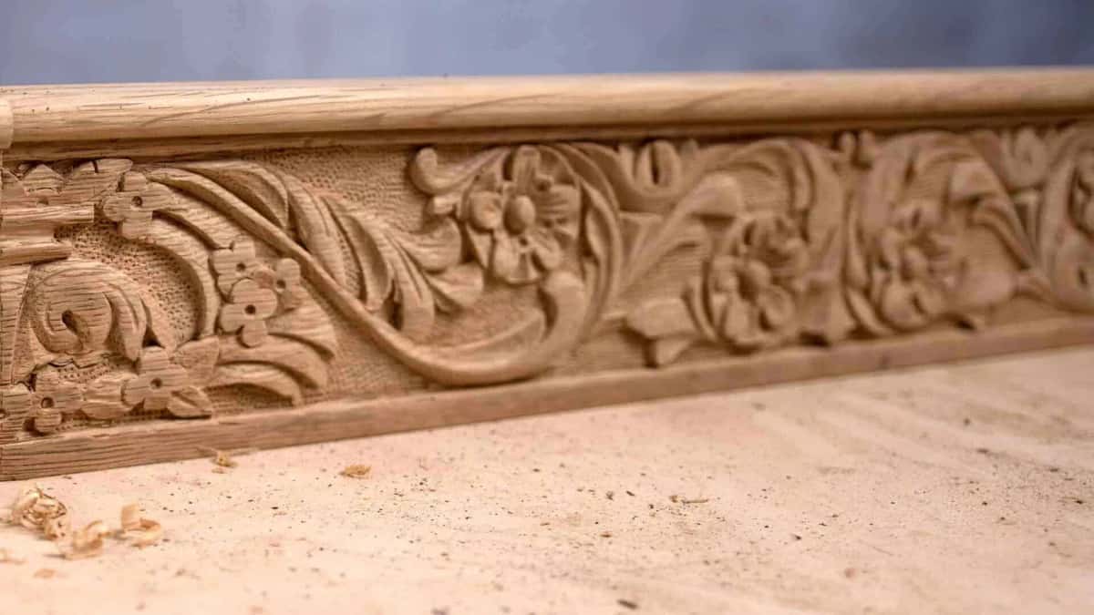 Long carved moulding, an acanthus scroll with small flowers standing over a stippled punched ground of tiny dots