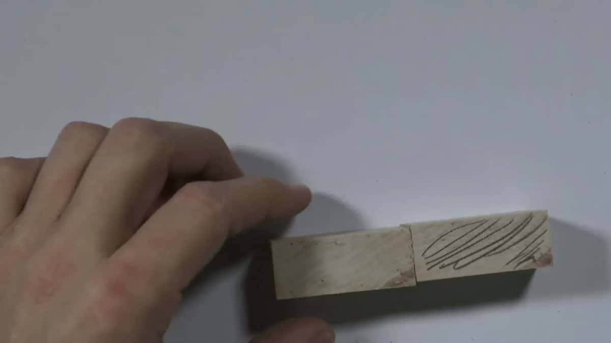 A hand turning a basswood block to show growth rings drawn on its end grain