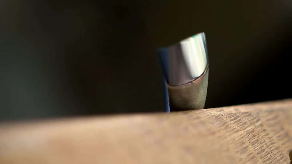 A spoon gouge resting on the stone, shot close enough that the bevel fills the frame