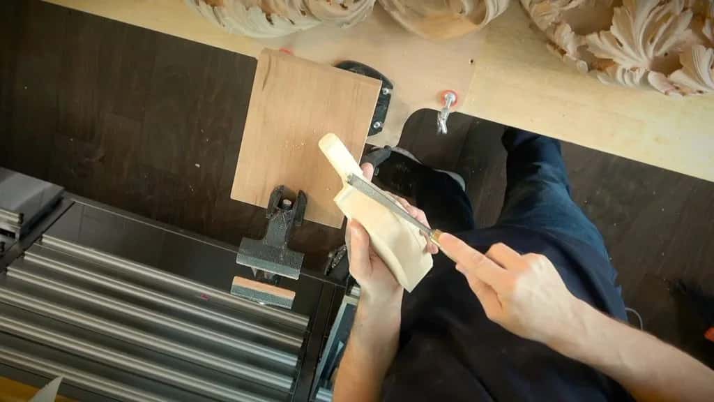 A carved element held up over the machine table