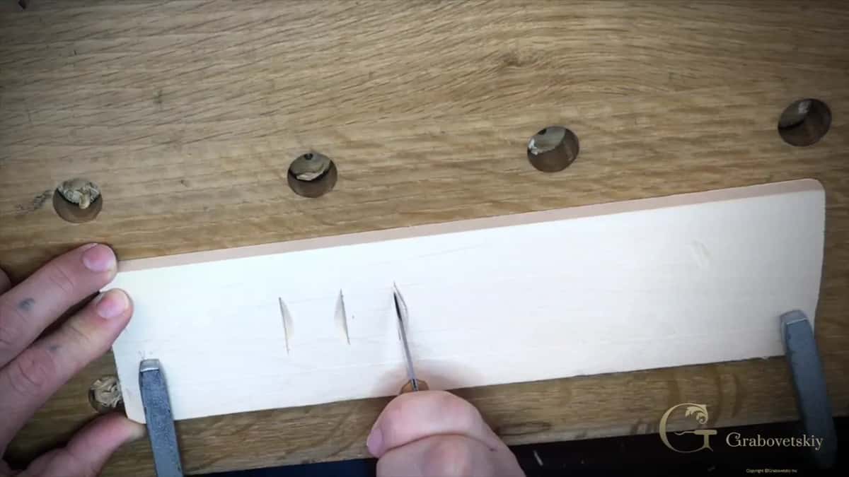 Two clean chips already lifted out of the board and the knife starting the third