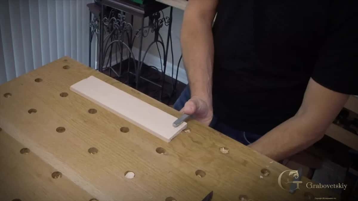 Practice board held flat on the bench with the blade brought to its near edge
