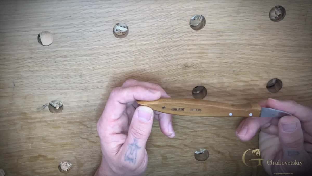 Hands holding the number 12 Swiss made carving knife with the maker stamp showing on the handle