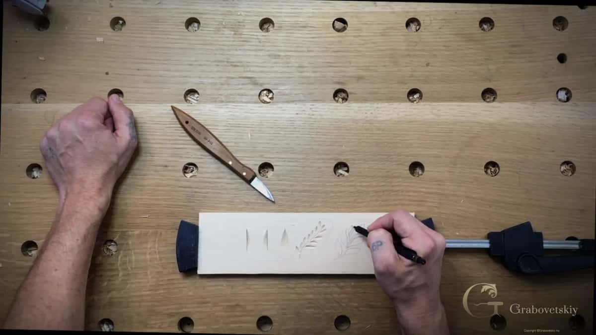Carved leaf shapes on the practice board while a new leafy design is drawn beside them