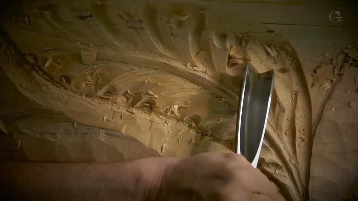 Wide gouge standing upright in a hollow of the acanthus, with fresh chips all around it
