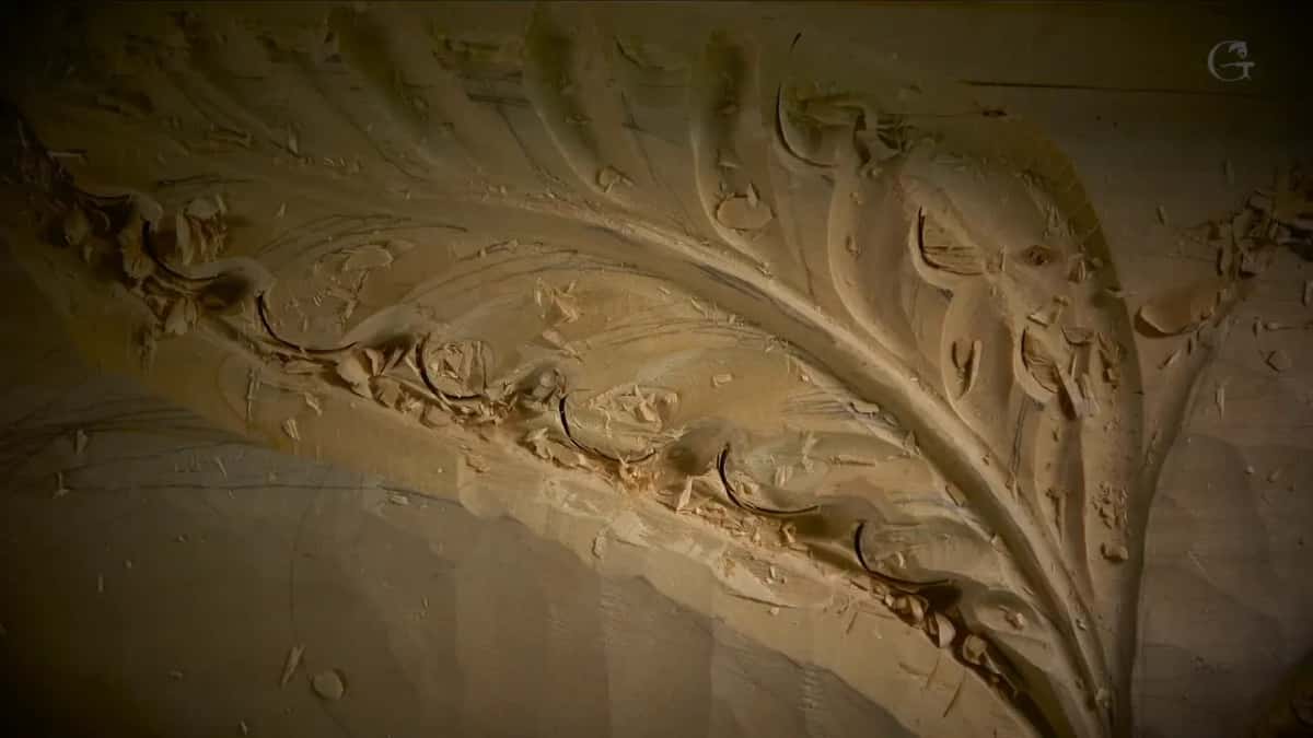 Chips scattered across the carved form, with the fluted leaves curving up to the right