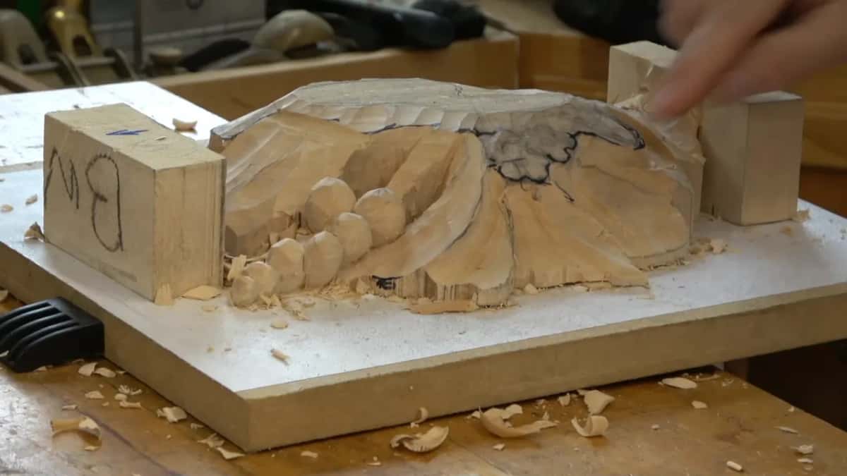 Rounded gouge running an outside boundary, upside down, the shaving lifting ahead of the edge