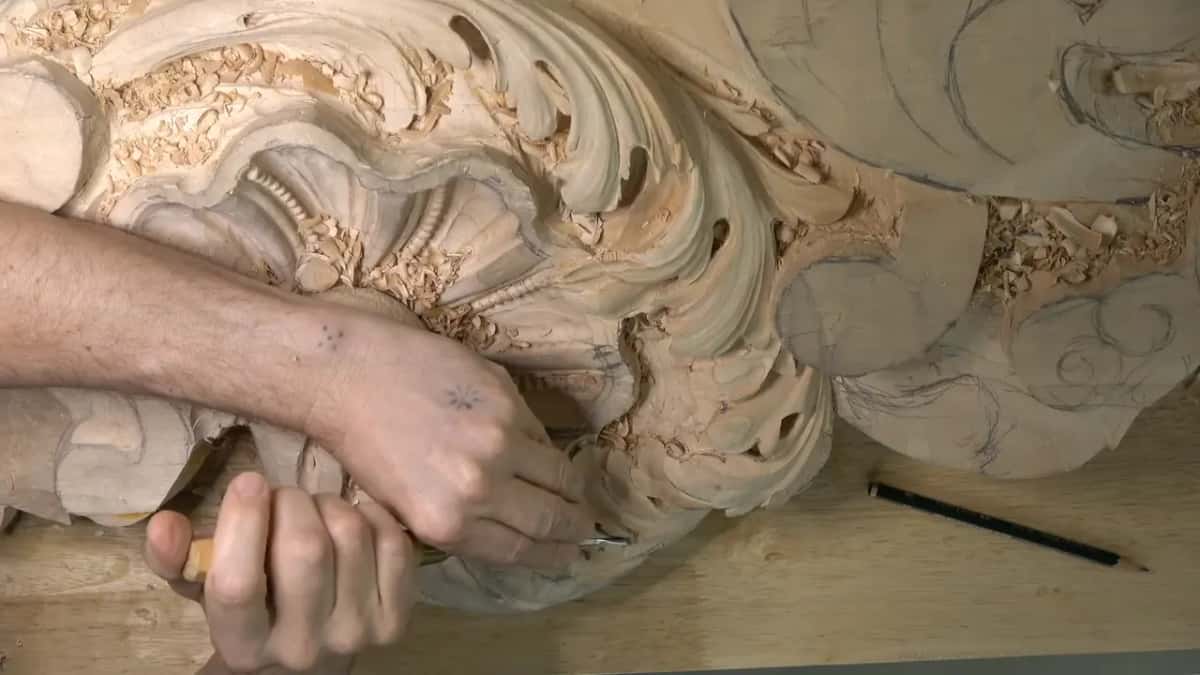 Both hands on a short yellow gouge at the lower left lobe of the head.
