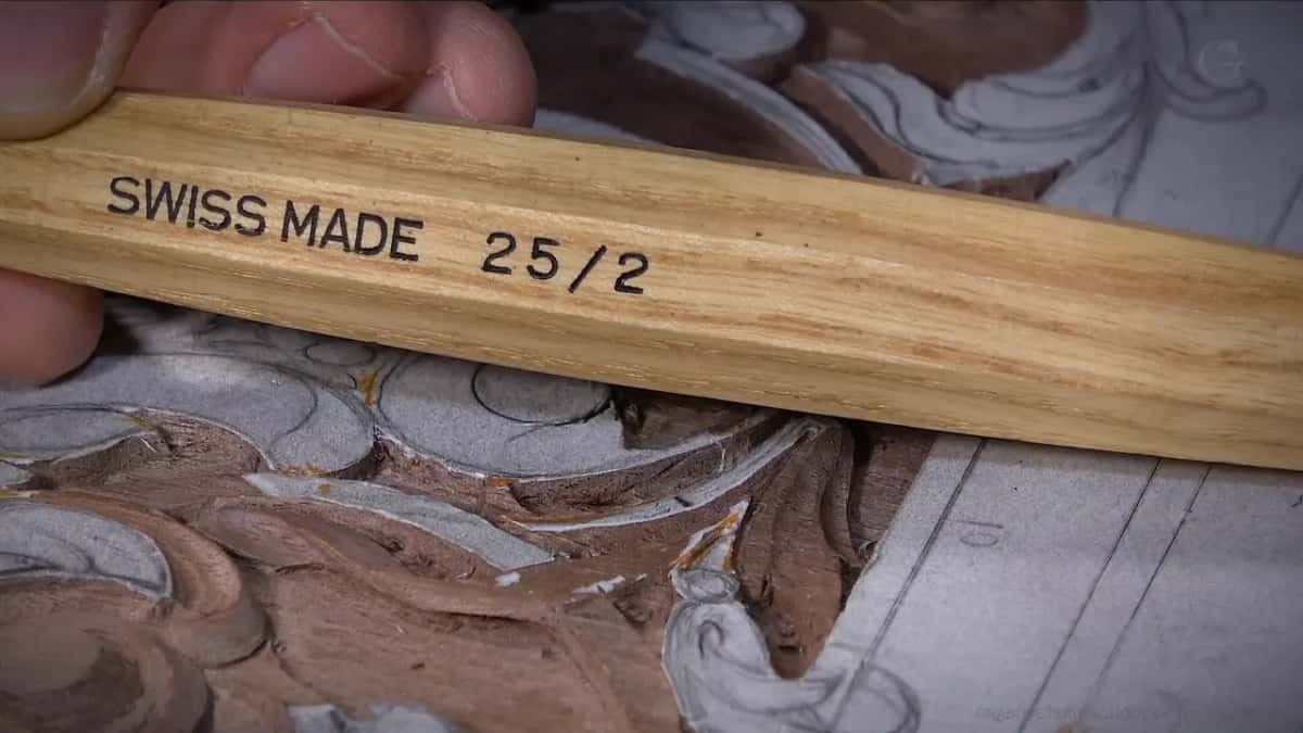 Handle held up to the camera, the stamp reading SWISS MADE 25/2 across the pale wood
