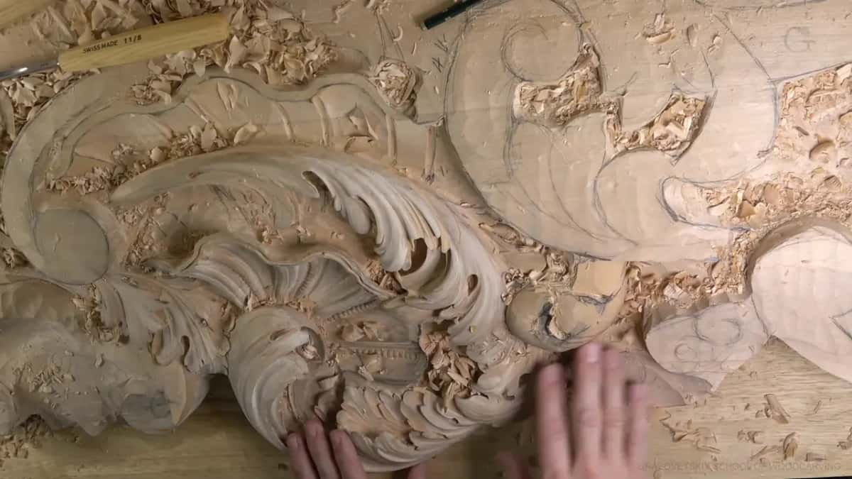 Seen from above, the whole acanthus head lies on the bench, two hands resting at its lower edge.