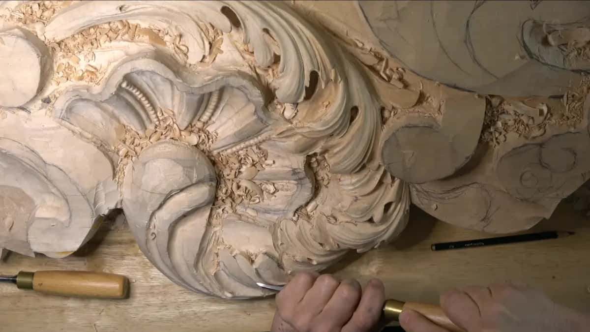 Resting on the bench, another gouge waits while both hands work along the bottom of the lobe.