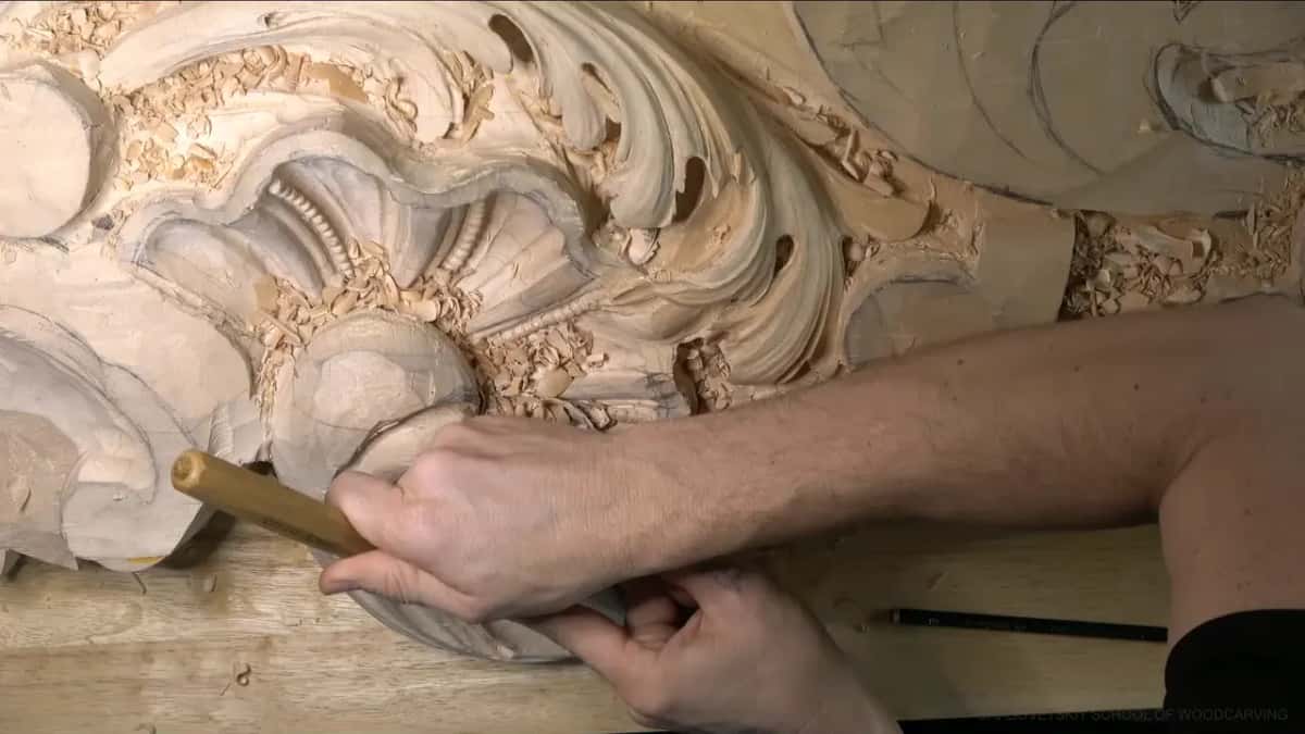 Knuckles low, both hands push a long handle along the left lobe while a pencil lies nearby.