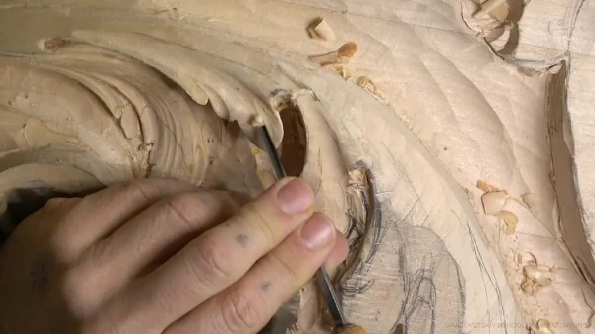 Straight gouge cutting along one side of a raised ridge.