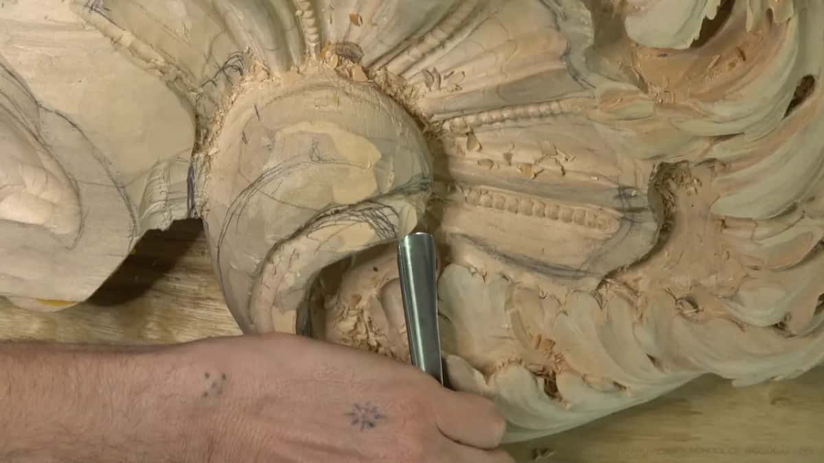From above, a straight gouge sits inside the curl of the head, with rows of beads carved beyond it.
