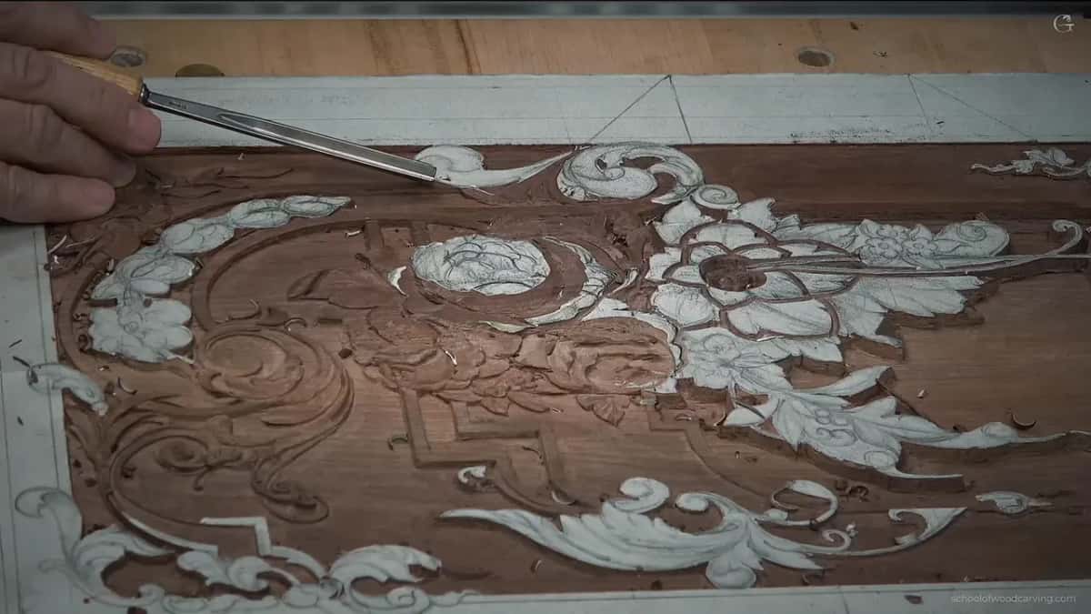 Whole panel from above, chalked ornament across dark walnut, one tool reaching in from the left.