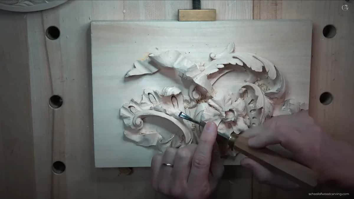 Edge set into the relief, both hands steady on the tool.