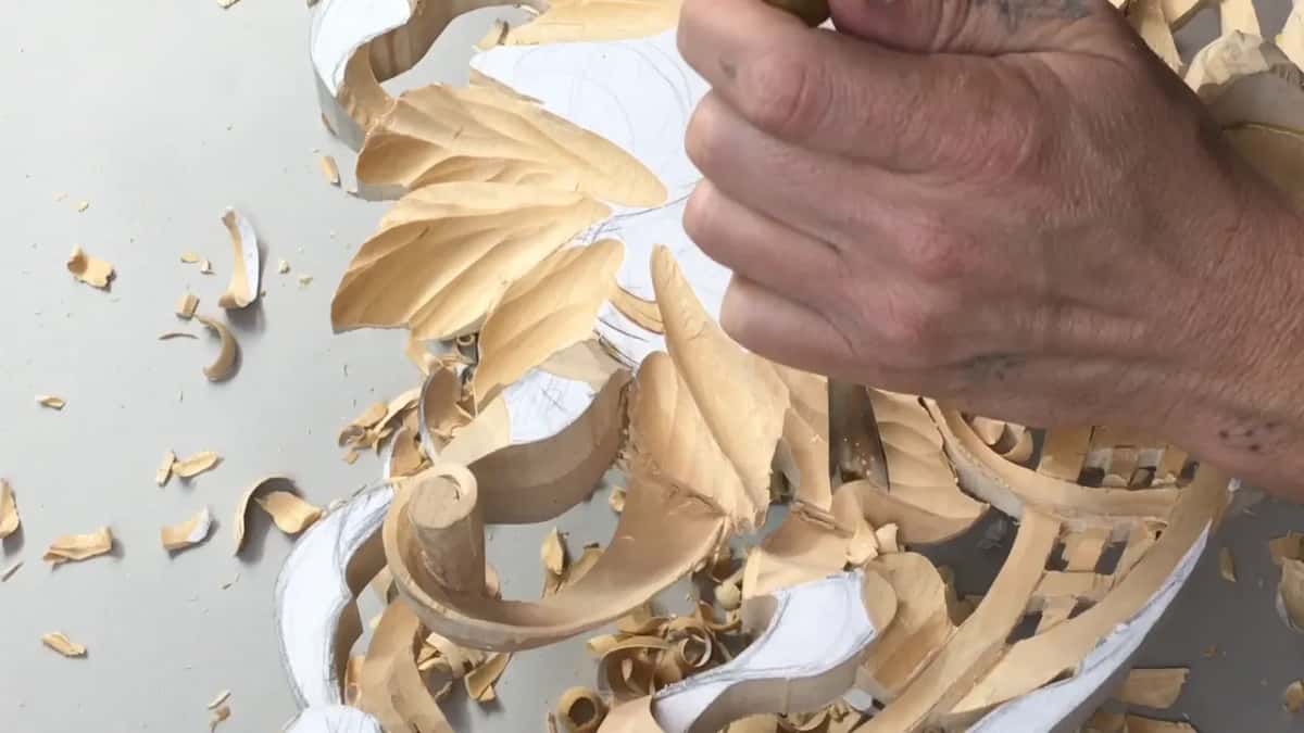 A hand gripping a handle over the leaves, chips lying on the bench