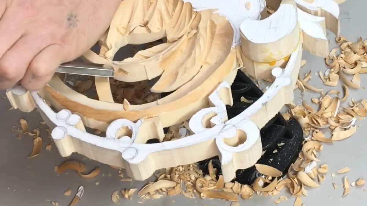 One hand with a flat tool at the rim, shavings spread around it