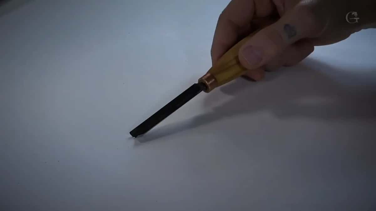 Gouge held by the handle, blade angled down.