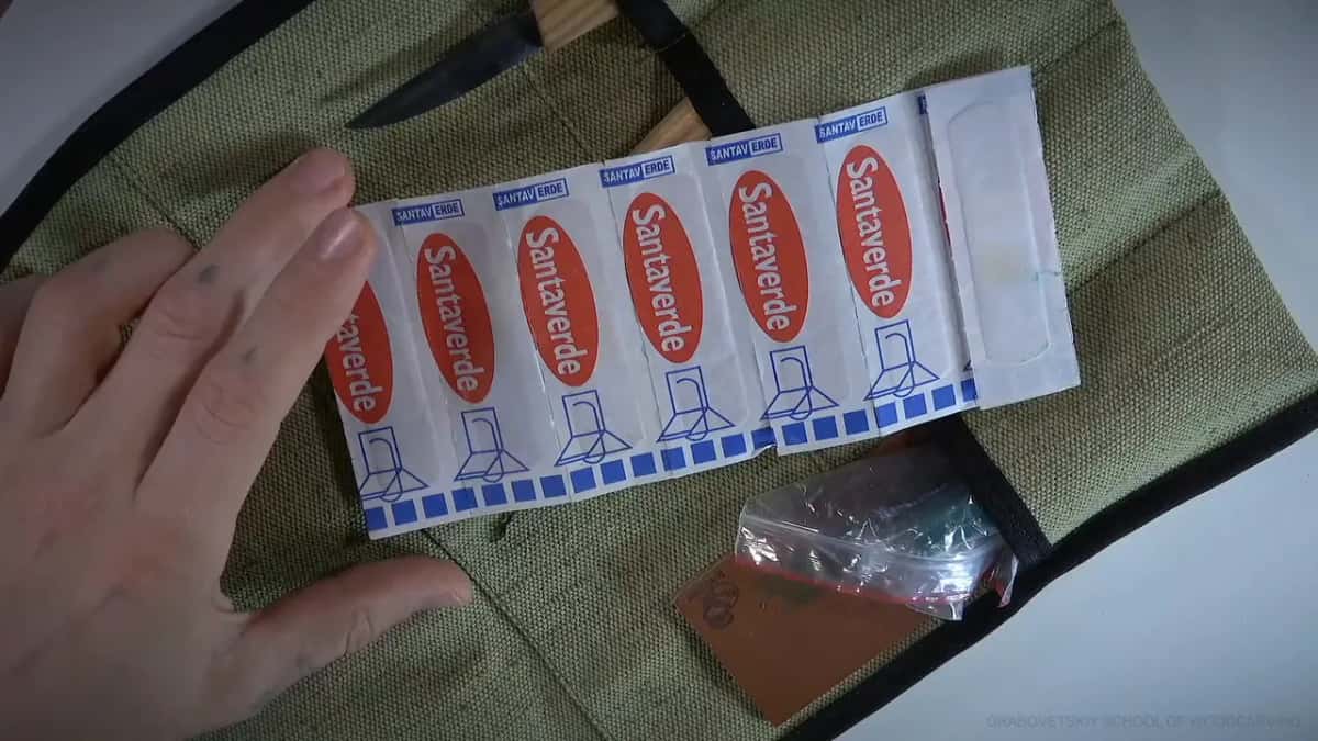 Strip of six wrapped Band-Aids, held over the open tool roll.