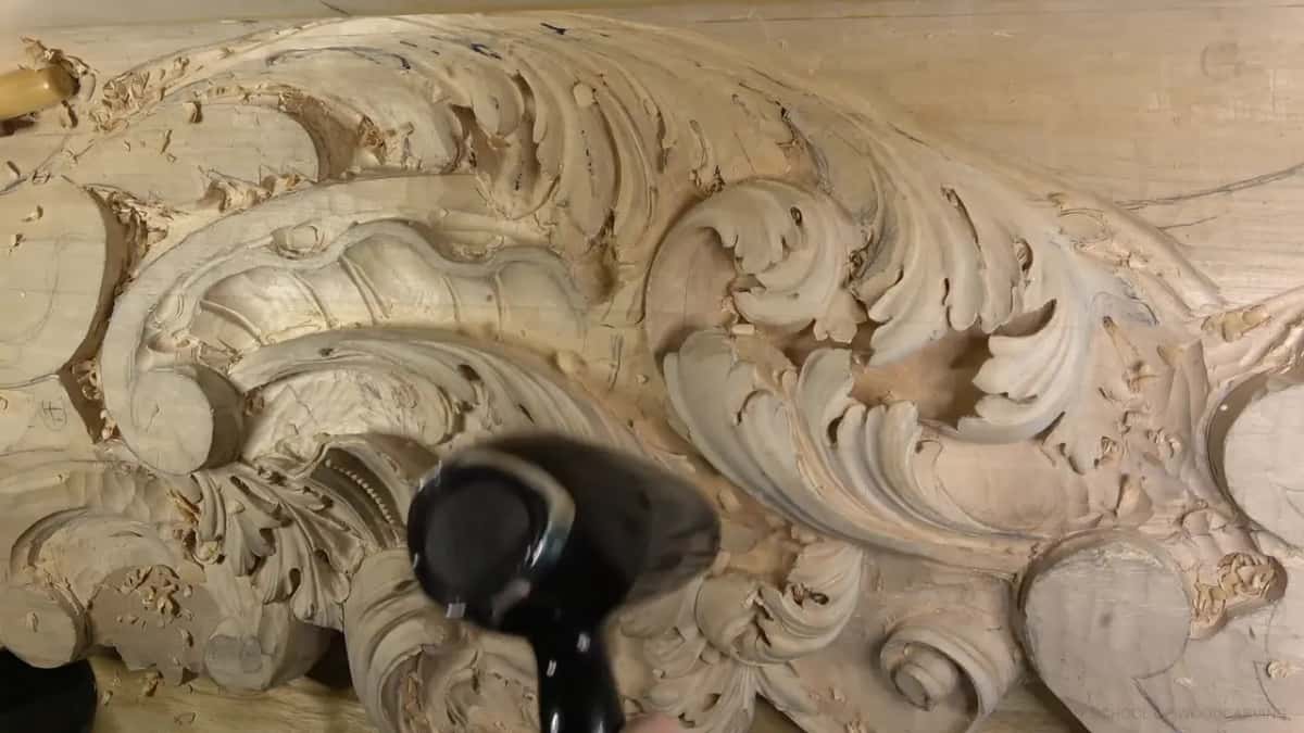 Black blower aimed at the carving, clearing chips off the scrolls and shells.