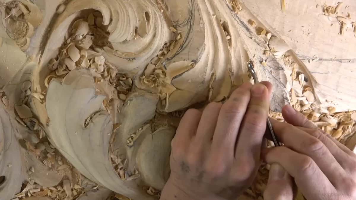 Both hands steer a thin tool along the wall of an upper lobe, chips scattered all around.