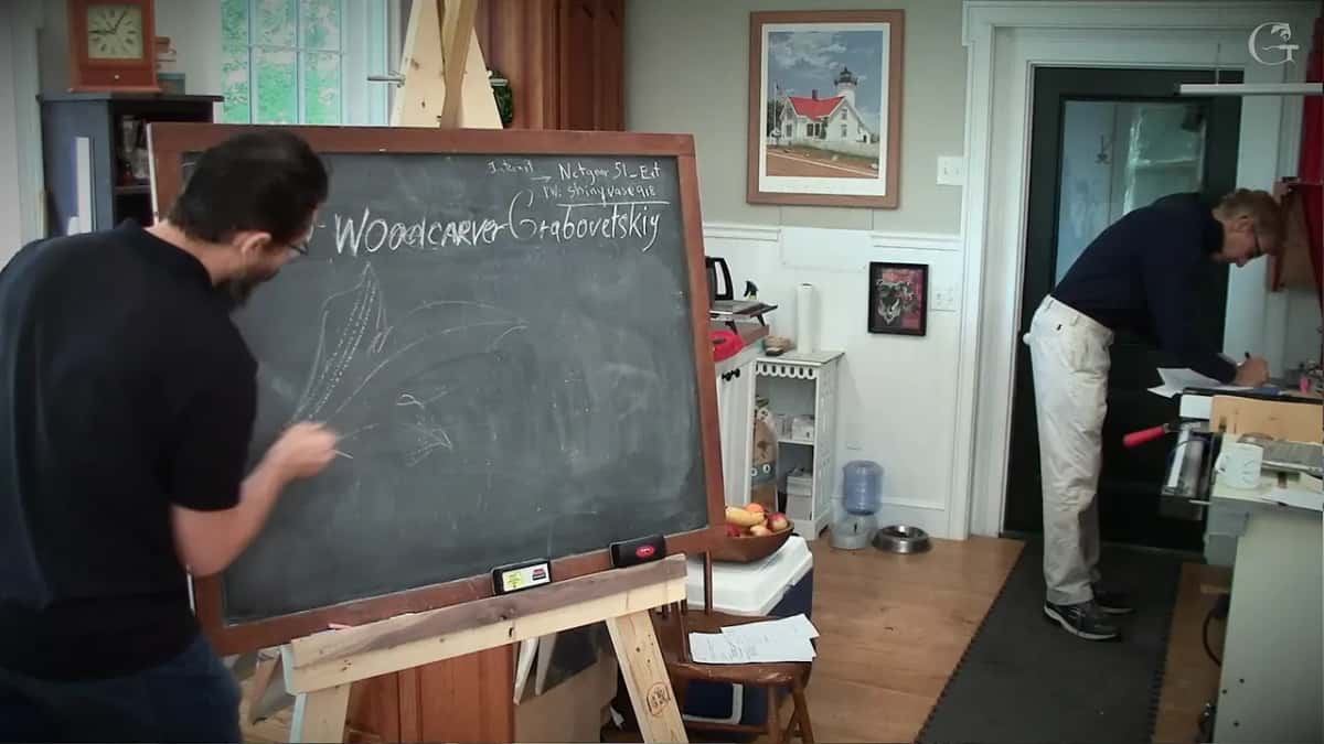 Drawing at the chalkboard while a student crosses the room behind him