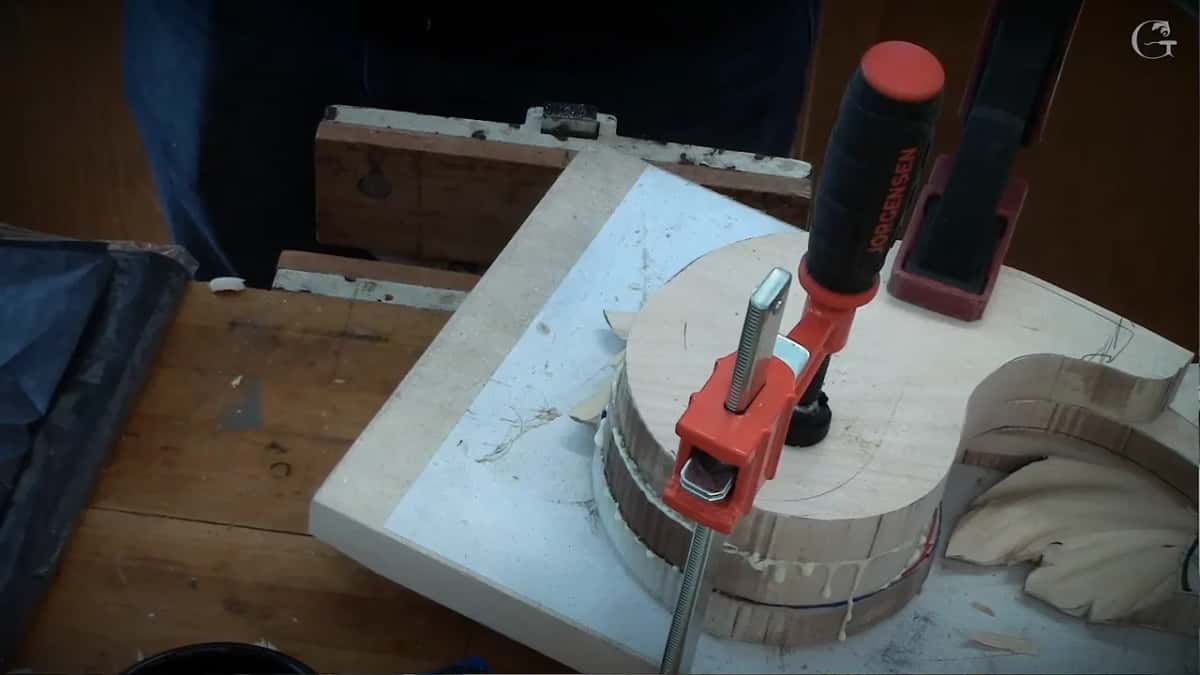 Two red clamps squeezing the glued stack against the white board