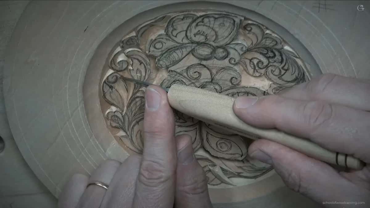 Both hands guide the knife low along a curl