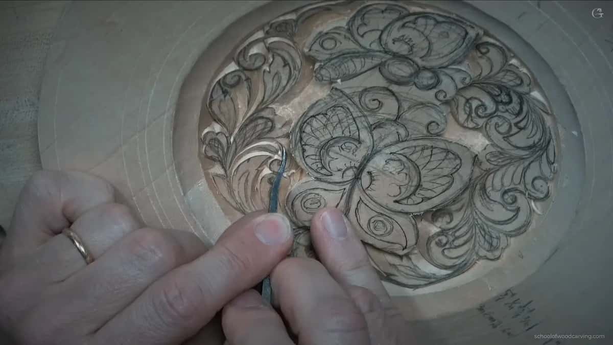 Small bent spoon gouge working beside the curls, left of the butterfly