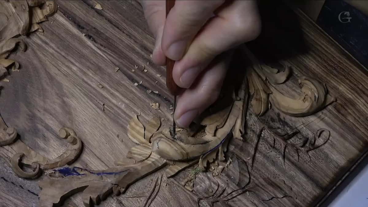 Red-handled micro gouge held upright, its point going into a curl low on the leaf