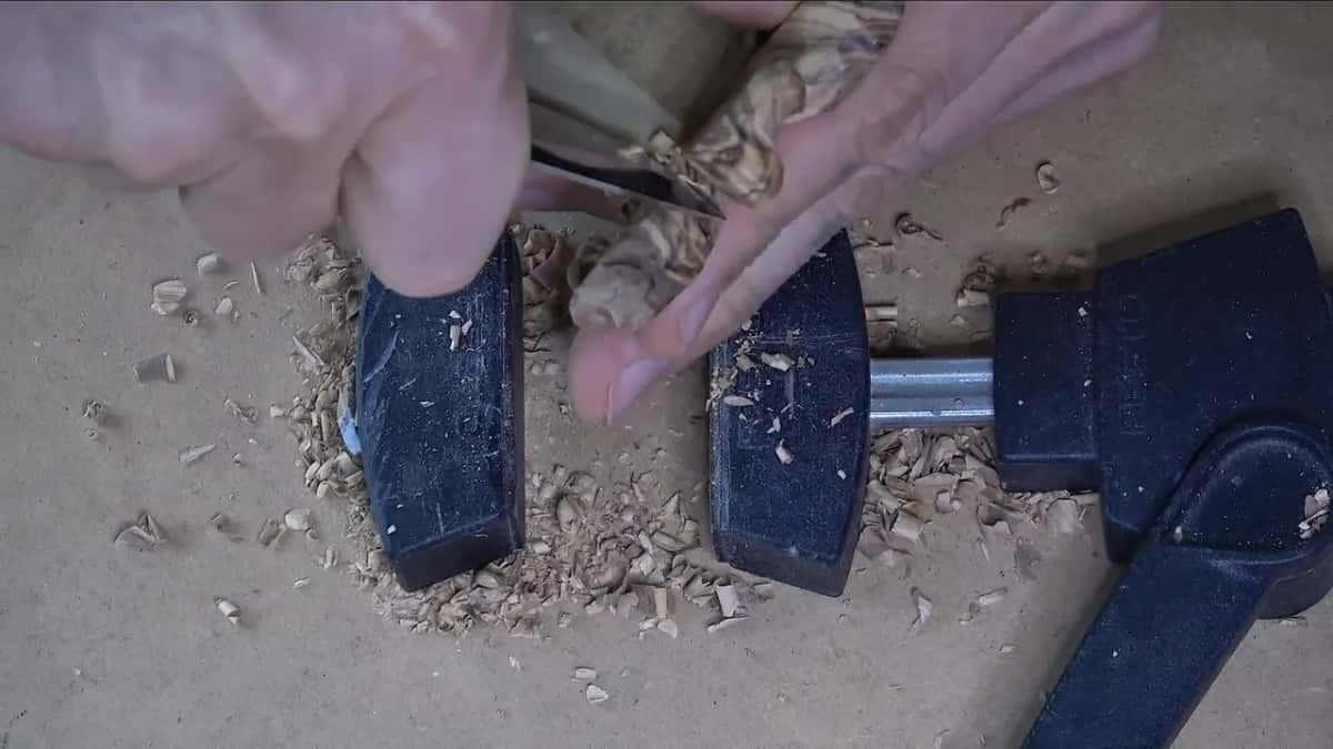 One finger tucked into the petal as a support while the other hand carves near its rim