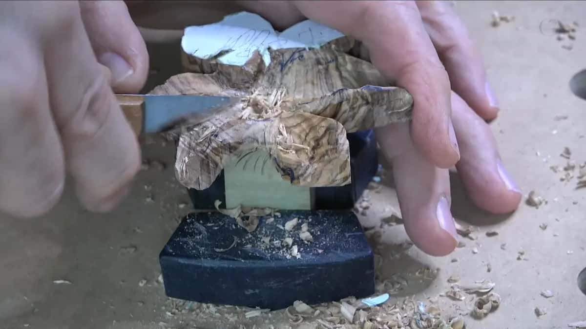 Knife shaving a petal edge, seen side-on, poplar block visible below the olive