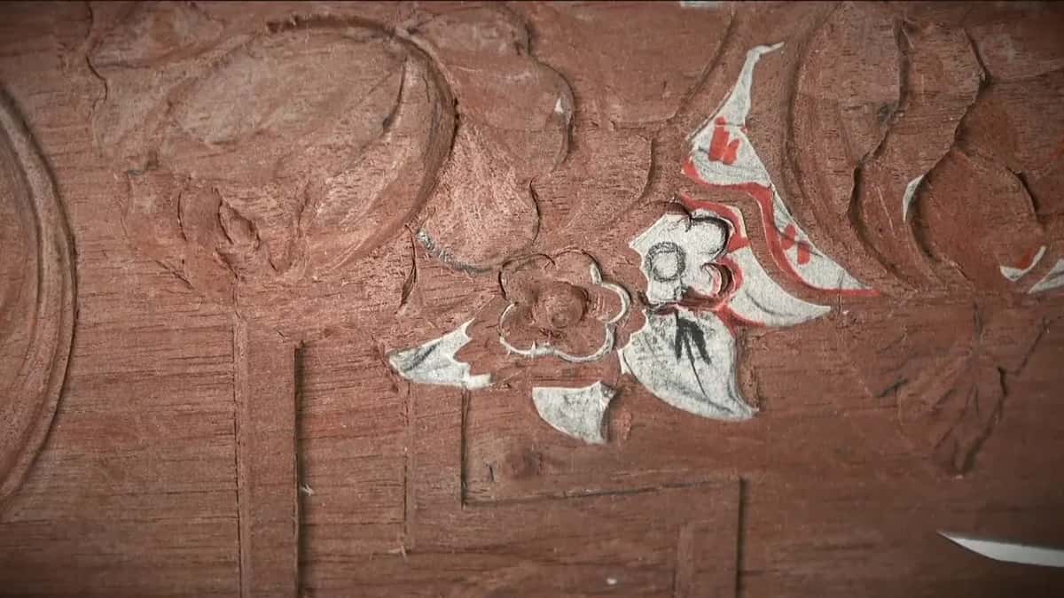 Tiny carved blooms in bare wood, red and white pattern paper still stuck beside them