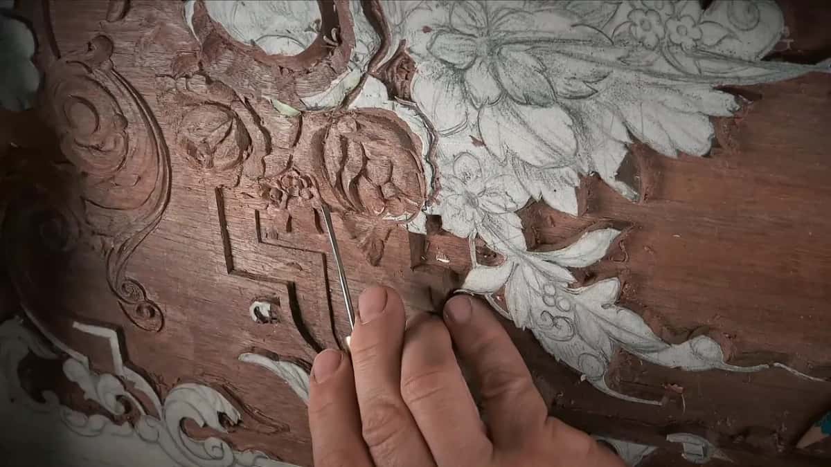 Slim blade standing up out of the carving, fingers braced along the board