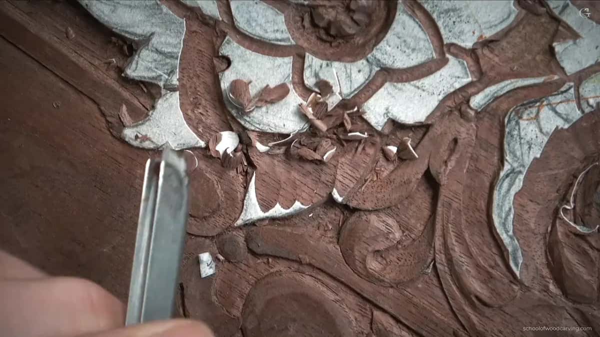 Bright steel lying right over the carving, turned so only one wing touches wood.