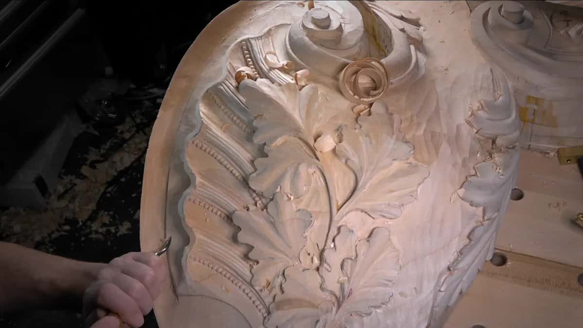 One hand works a small gouge into the left rim beside the shell ribs.