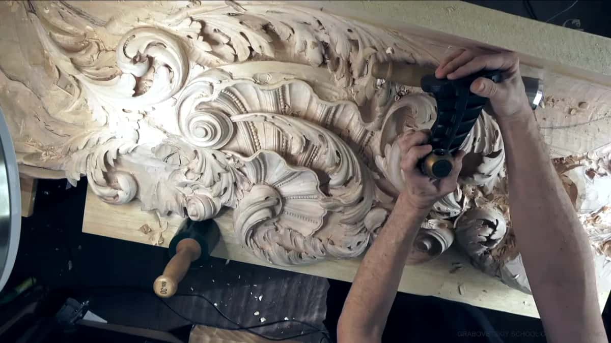 Black carver's vise held in both hands above the carved board.