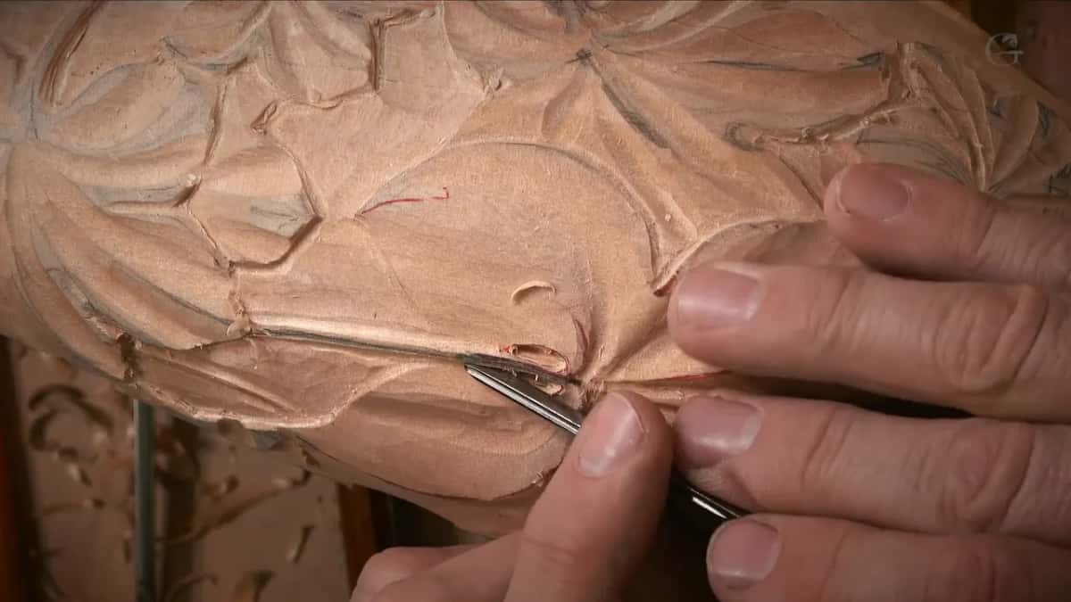 Fine gouge working along the middle of a leaf, red layout line still visible under the edge of it