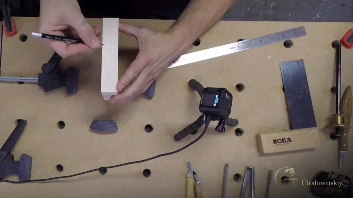 Steel rule against the edge of the blank, pencil finding the mark