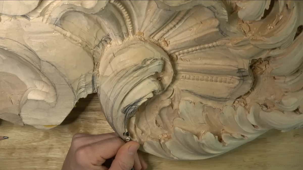 One hand holds a gouge low on the curl.