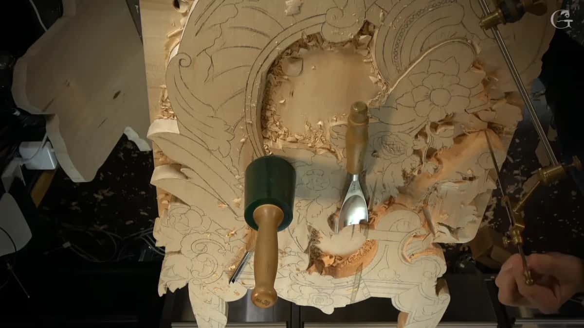Brass pointing machine reaching in from the right of the panel, a mallet and a spoon gouge lying on the carving