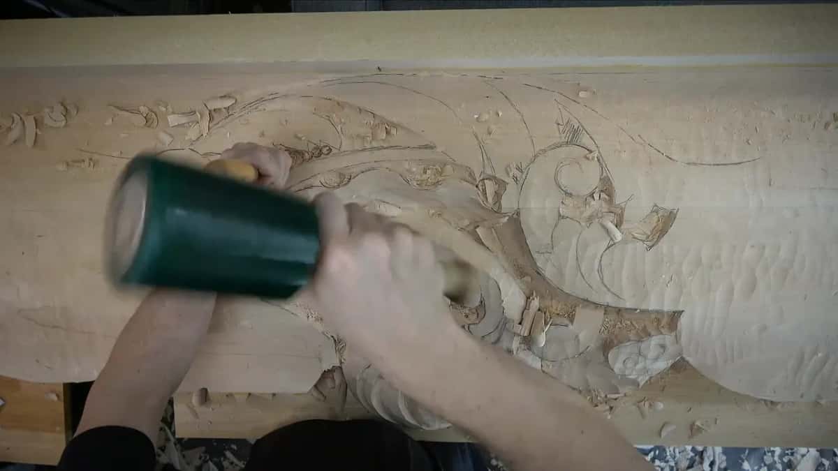 Green rubber mallet swinging onto the gouge.
