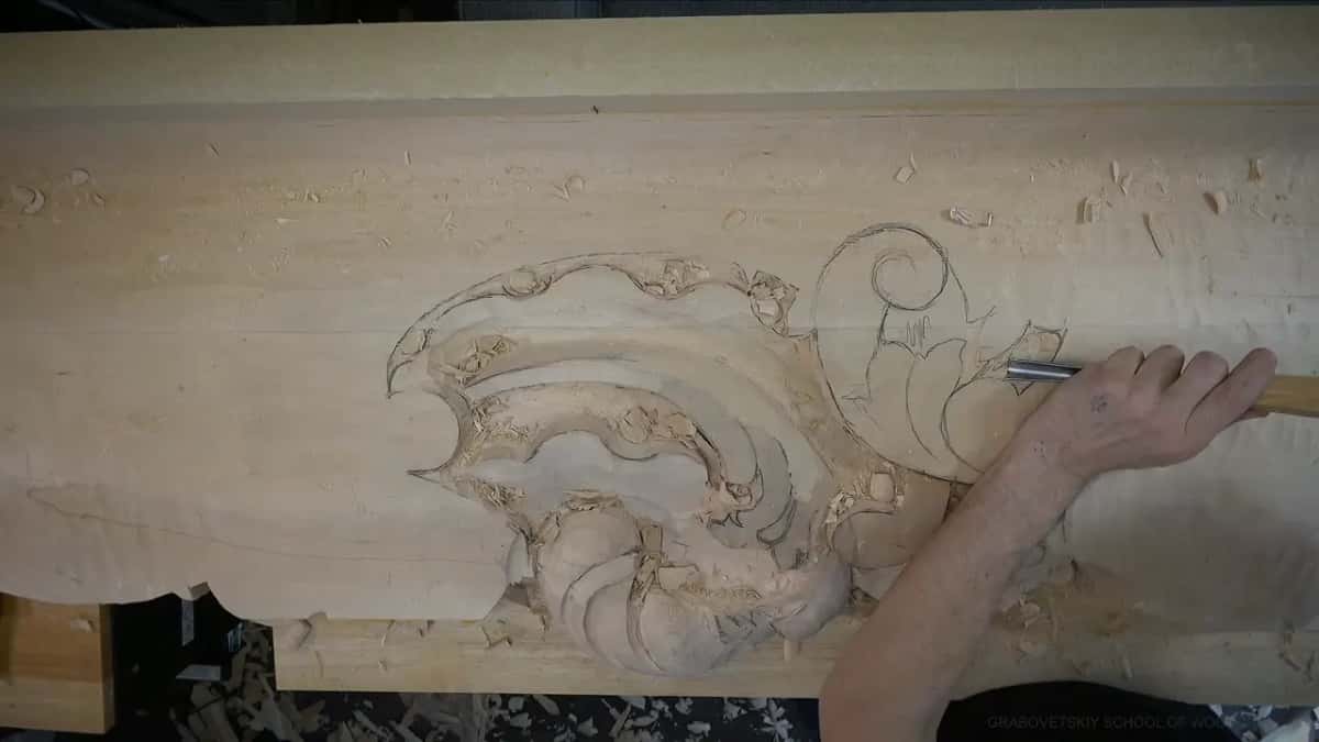 A narrow gouge works one small spot by a scroll.
