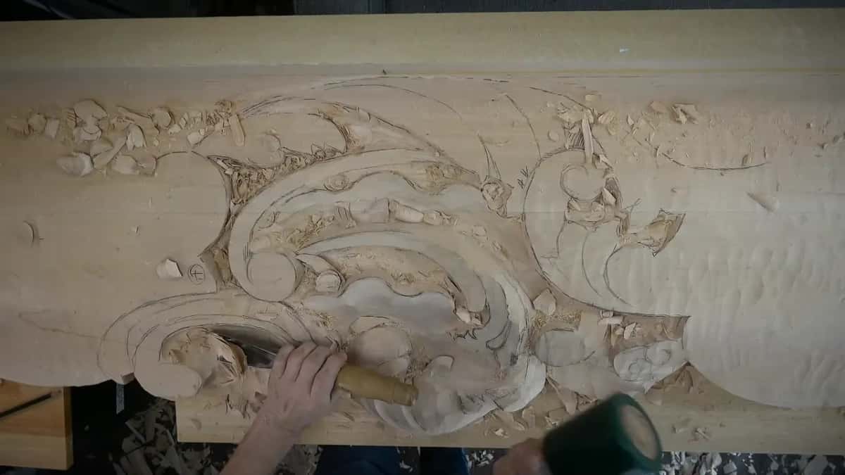 From above, a very wide gouge works the lower left of the carving, next to the curling scrolls.