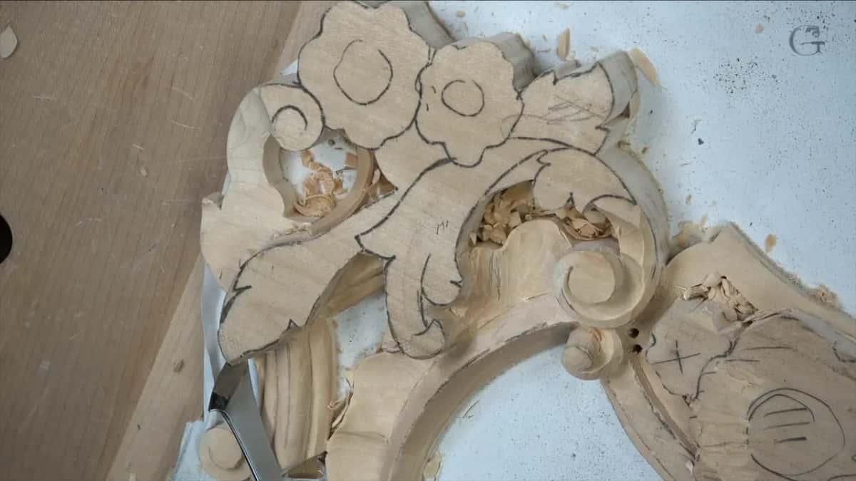 Panel half carved, molding band sweeping across the bottom, flowers above still drawn in pencil and waiting