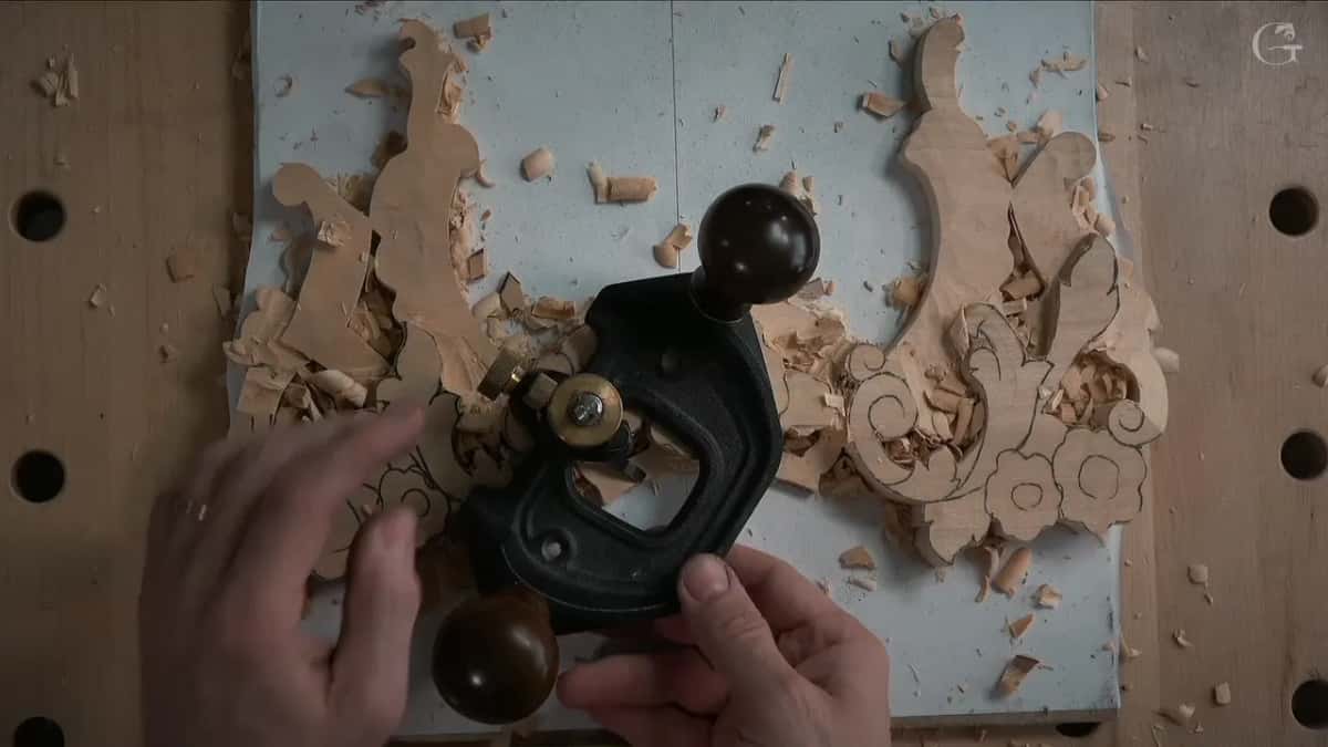 Black cast iron router plane, both hands on the knobs