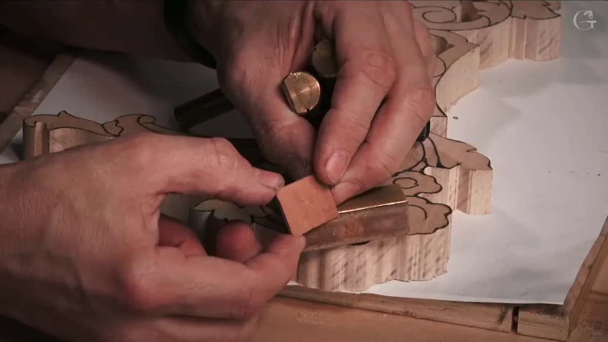 Two solid brass bench pegs in his hands, one with a leather pad glued to its face