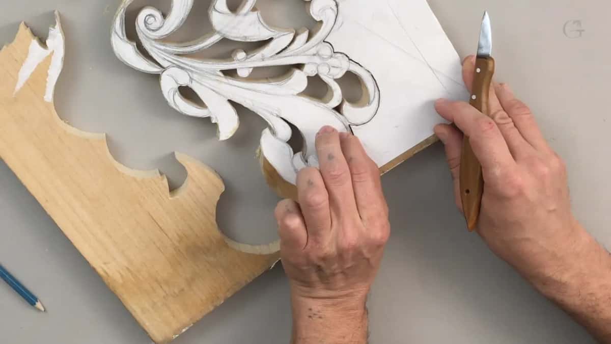 Both hands peeling the paper pattern away, with a sawn offcut lying beside